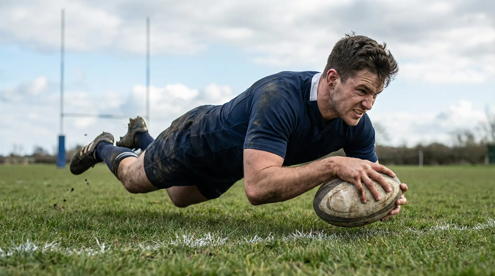 Joueur de rugby marquant un essai en plongeant derriere la ligne